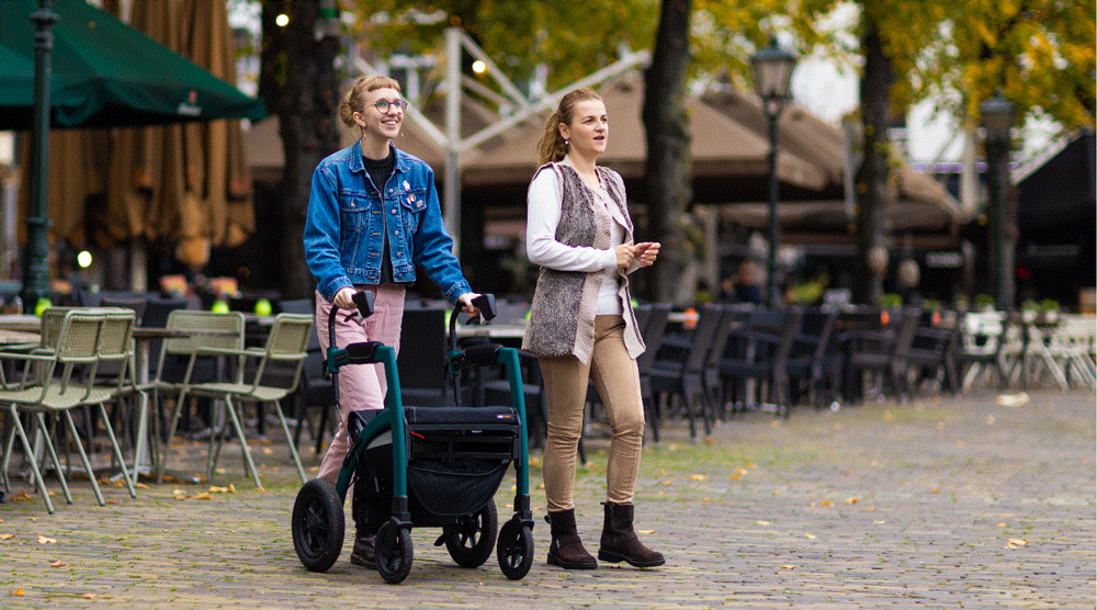 Woman walking with a rollator with pneumatic tires ion cobblestones n an old city